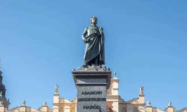 Pomnik Mickiewicza, symbol romantyczności, na tle Sukiennic. Streszczenie epoki w kamieniu i architekturze.