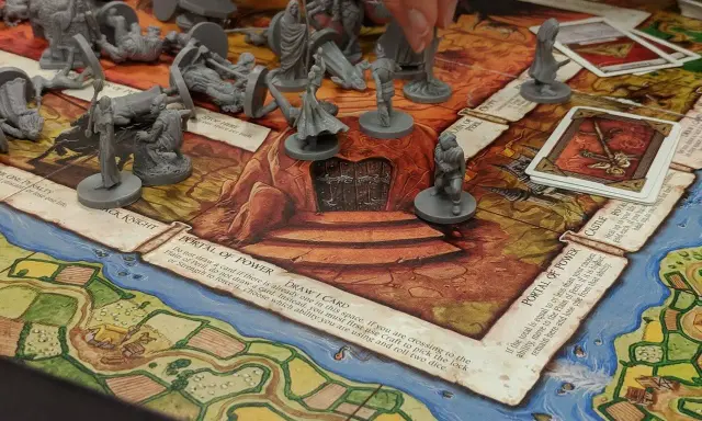 Gra planszowa RPG dla początkujących z figurkami i kartami. Gracze poruszają pionkami po planszy, walcząc i zdobywając przedmioty.
