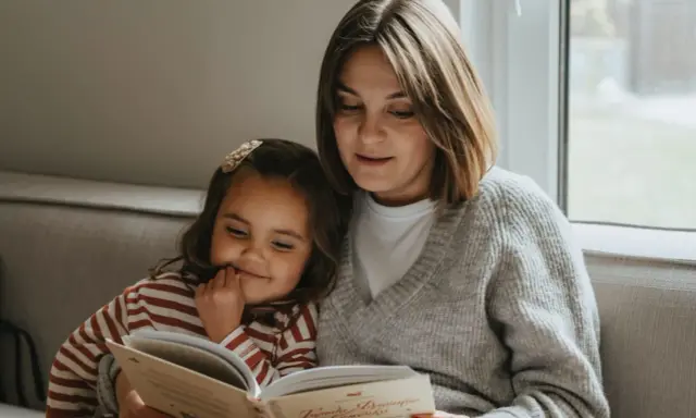 Mama czyta dziecku bajkę, pokazując, jak zachęcić dziecko do czytania. Wspólne chwile z książką budują więź i rozwijają wyobraźnię.