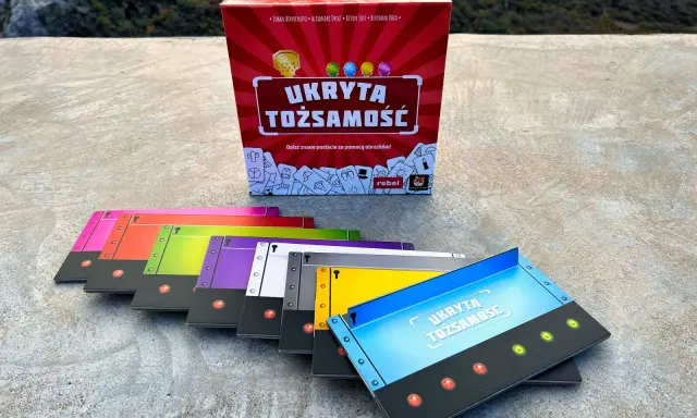 Gra "Ukryta tożsamość" w pudełku i kolorowe karty do gry.