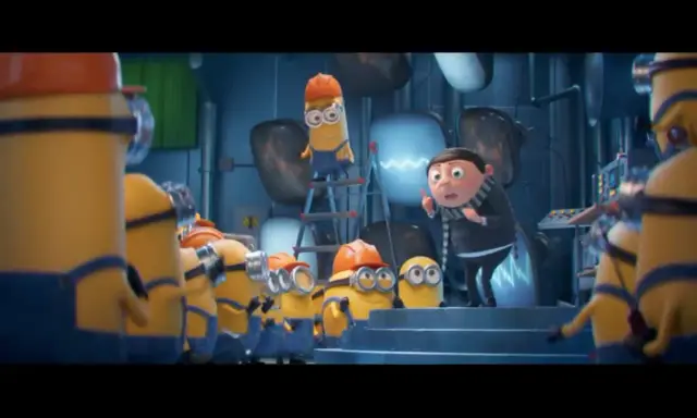 Gru przemawia do grupy minionków, które pracują w laboratorium. Widać różne minionki części, niektóre w kaskach.