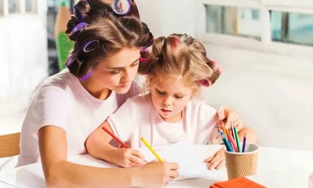 Mama i córka z wałkami na włosach rysują kredkami. Wspaniałe zabawy dla dzieci w domu 10 lat i młodszych.