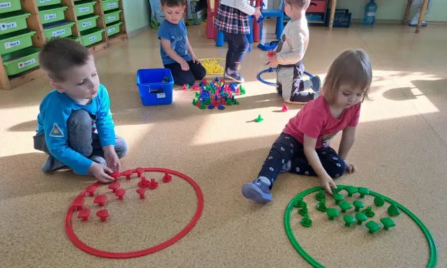 Dzieci w przedszkolu bawią się klockami, tworząc wzory w obręczach. To świetne zabawy dla 3 latka w przedszkolu.