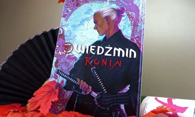 Komiks "Wiedźmin: Ronin" z Geraltem w japońskim stylu, otoczony jesiennymi liśćmi i wachlarzem.