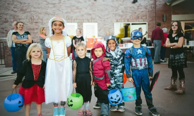 Dzieci w strojach na Halloween, gotowe na psikusy i zbieranie słodyczy. Wśród nich księżniczka, Kapitan Ameryka i inne postacie.