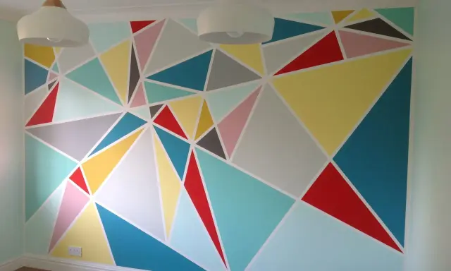 Kolorowe malunki na ścianie dla dzieci w geometryczne wzory. Radosna, pastelowa paleta barw tworzy wesołą atmosferę.