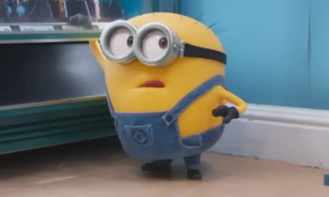 Minionek w ogrodniczkach zastanawia się, po jakim języku mówią minionki, gdy patrzy na automat z przekąskami.