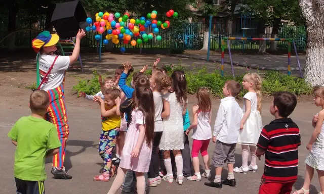 Animator wypuszcza balony, dzieci łapią je z radością. Świetny pomysł na urodziny dla dzieci na świeżym powietrzu!