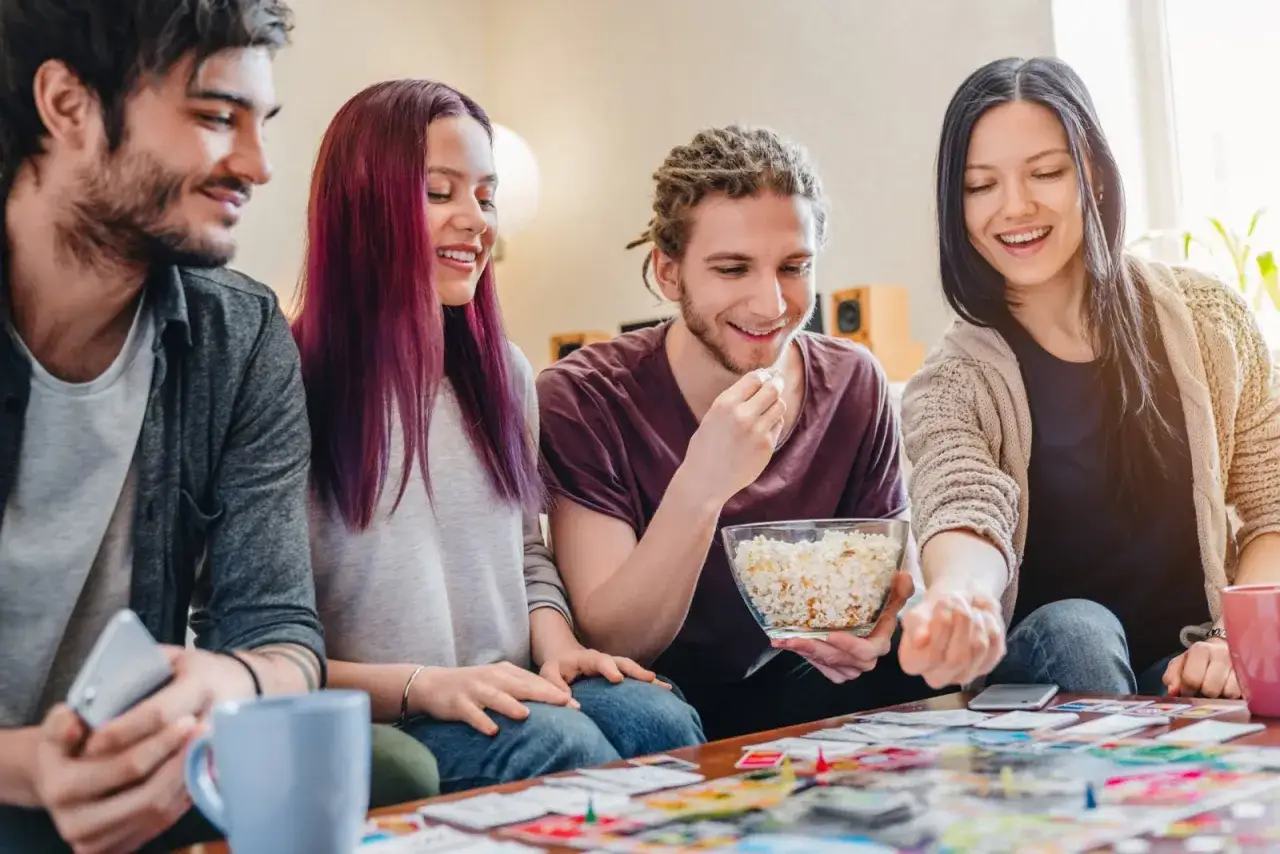 Czterech przyjaciół gra w planszówkę, jedząc popcorn. Czas na śmiech i wspólne pytania do przyjaciółki.