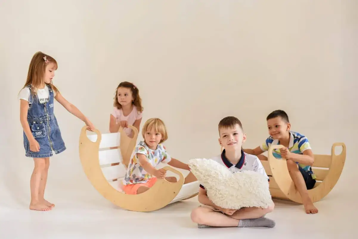 Dzieci cieszą się drewnianymi huśtawkami i poduszkami, doświadczając spokoju podczas zabaw wyciszających Montessori.
