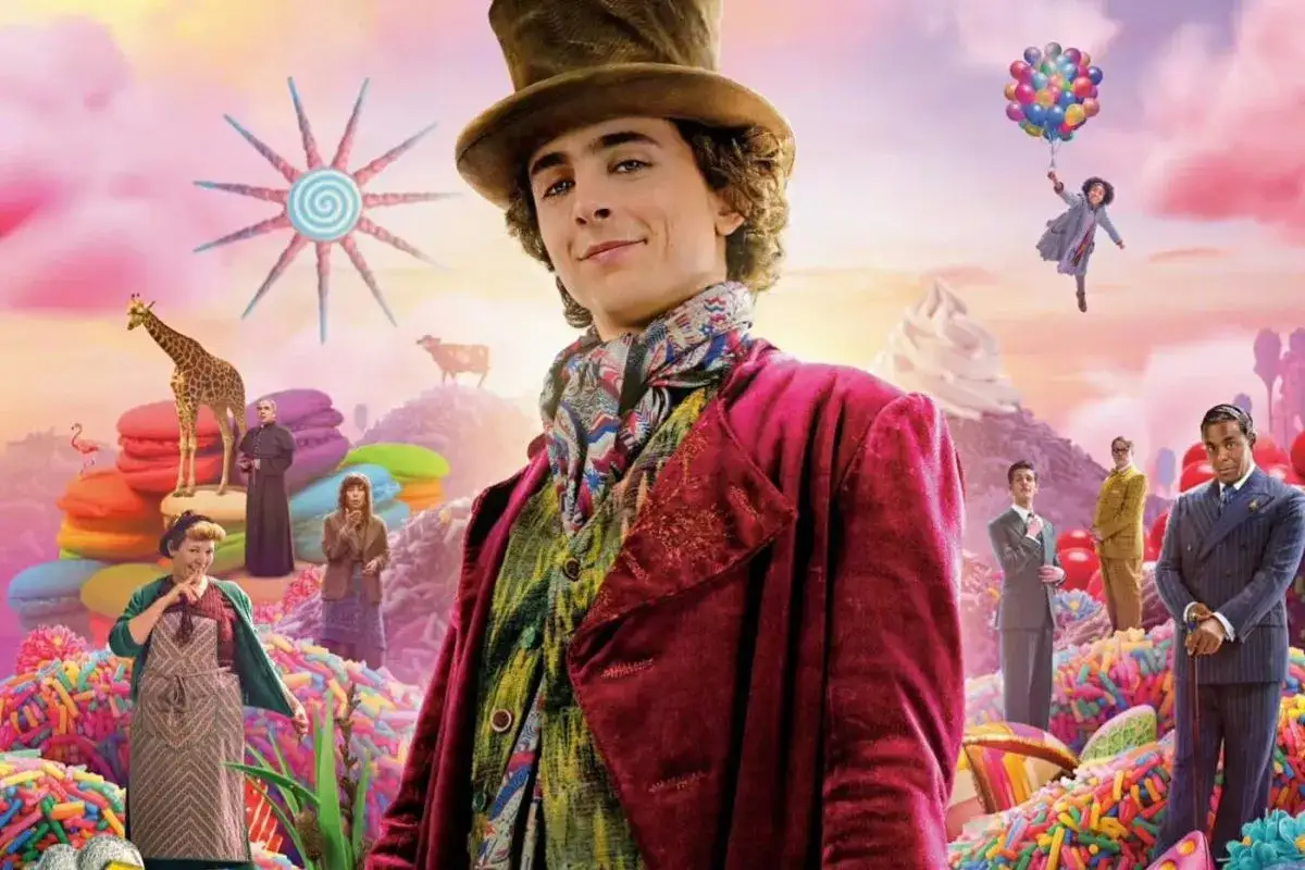 Młody Willy Wonka w wiktoriańskim stroju, otoczony przez fantastyczny świat słodyczy i postaci z filmu.