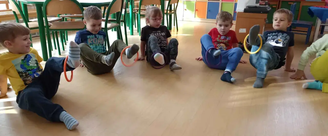 Dzieci w przedszkolu bawią się k&oacute;łkami, ćwicząc koordynację. To świetne zabawy dla 6 latk&oacute;w w przedszkolu, rozwijające sprawność fizyczną.