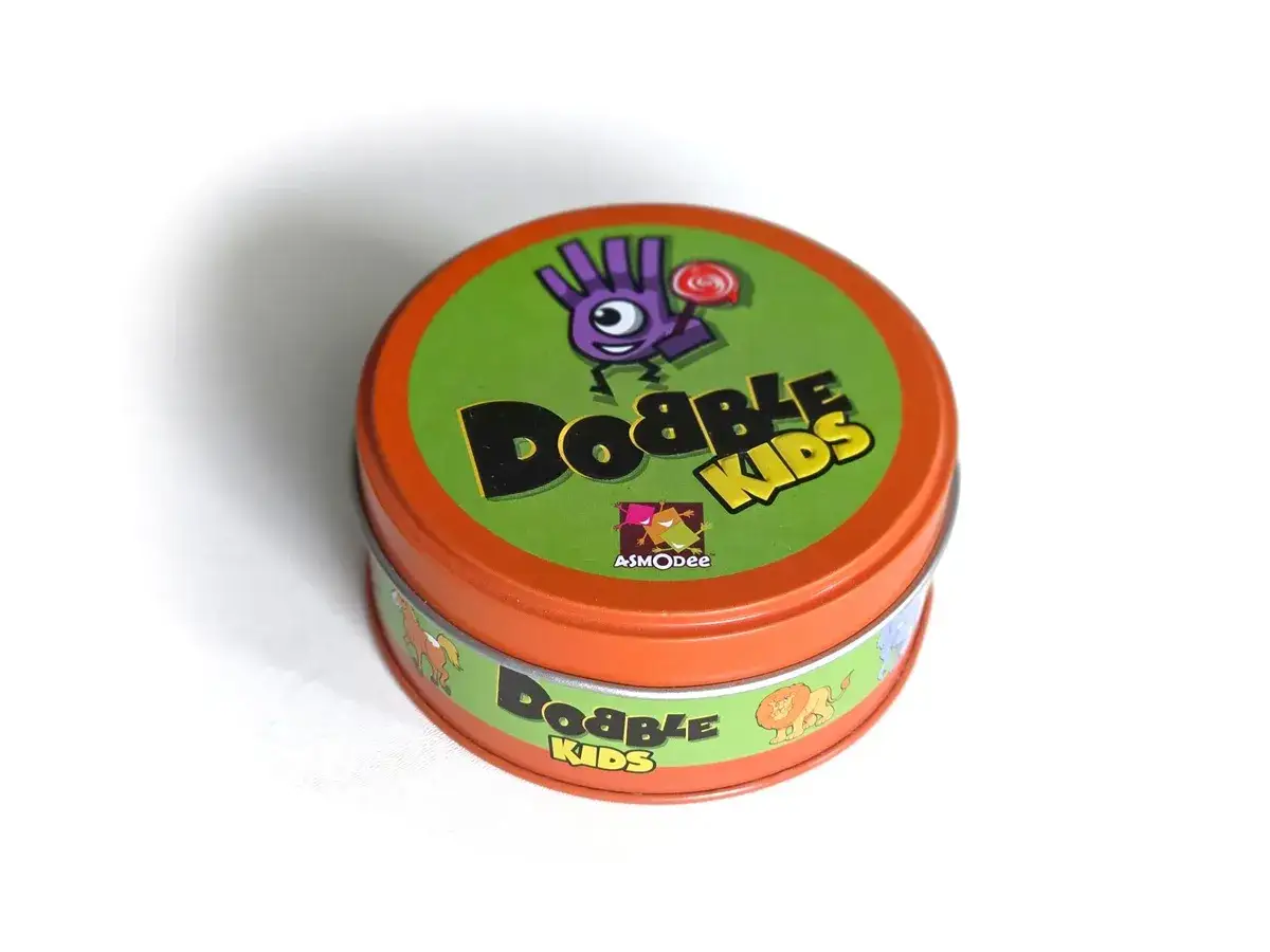 Pudełko gry Dobble Kids z zabawną grafiką. Poznaj zasady i baw się z dziećmi!