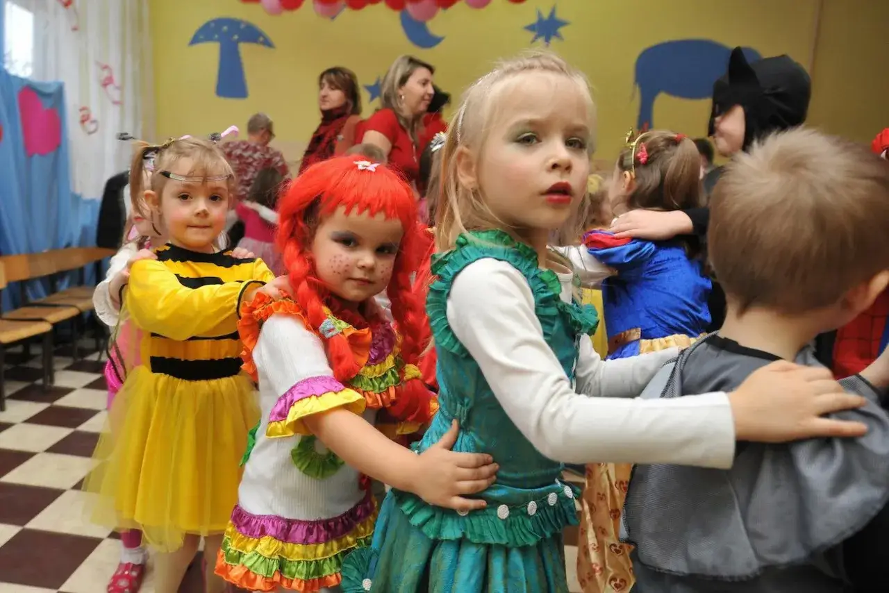 Dzieci w przedszkolu bawią się na balu karnawałowym. Wesołe stroje pszczółki, cyganki i księżniczki.