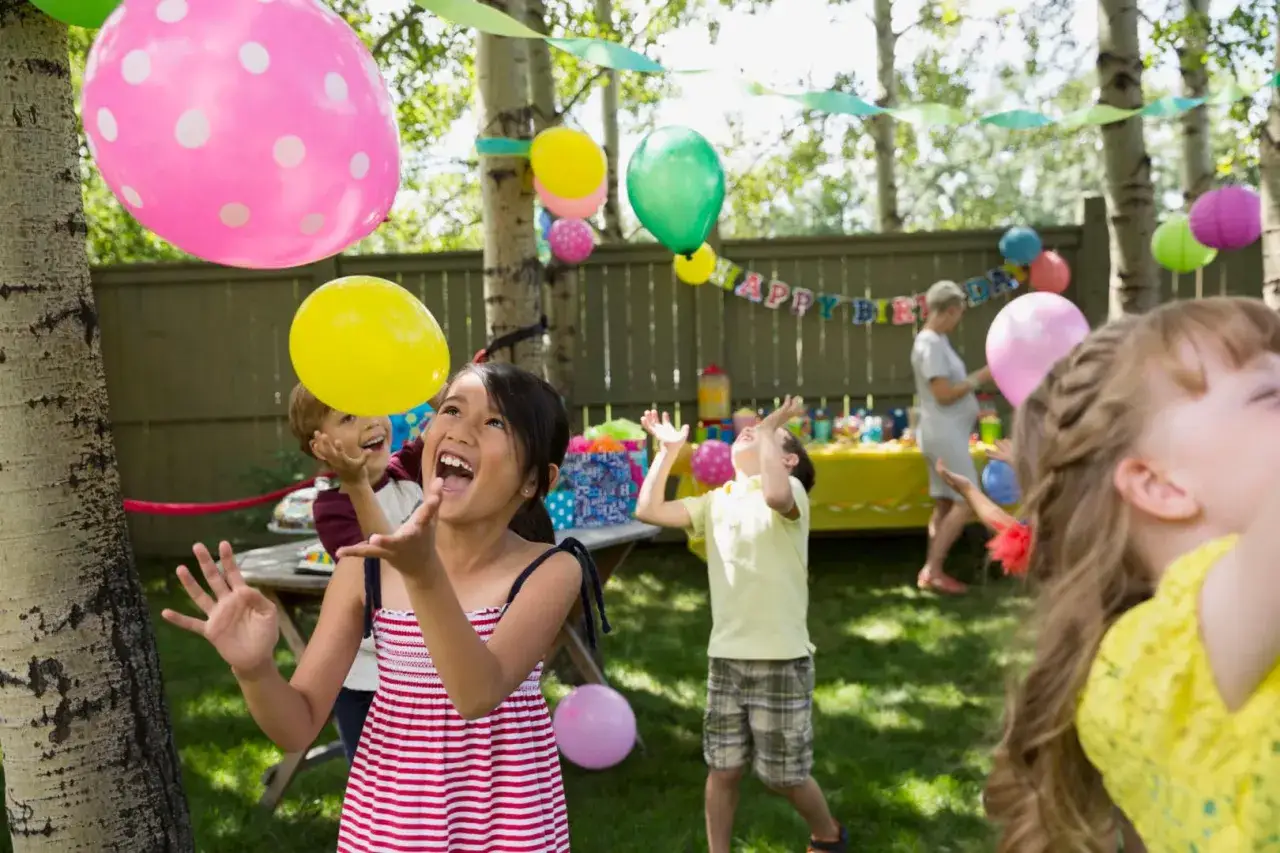 Dzieci bawią się balonami na przyjęciu urodzinowym. Radosne śmiechy i kolorowe balony tworzą atmosferę śmiesznych zadań dla dzieci na urodziny.