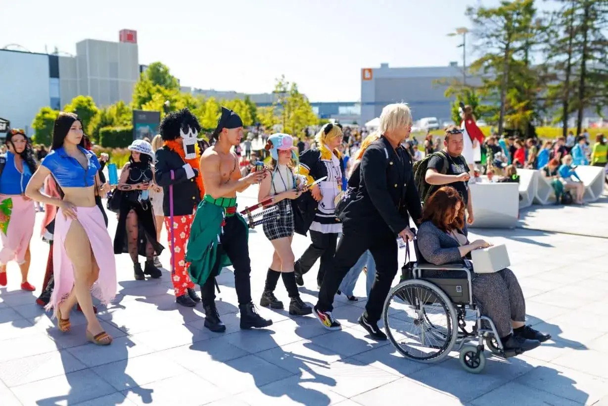 Grupa cosplayer&oacute;w, w tym postacie z anime, idzie ulicą. Wśr&oacute;d nich widać osoby z pyrkon tokeny.