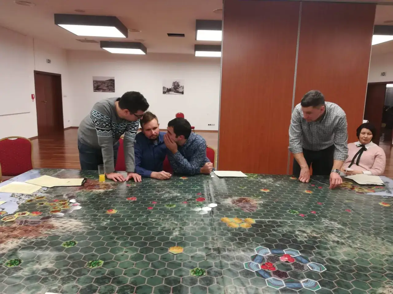 Ludzie grają w gry teambuildingowe na wielkiej planszy. Skupienie i strategia widać na ich twarzach.
