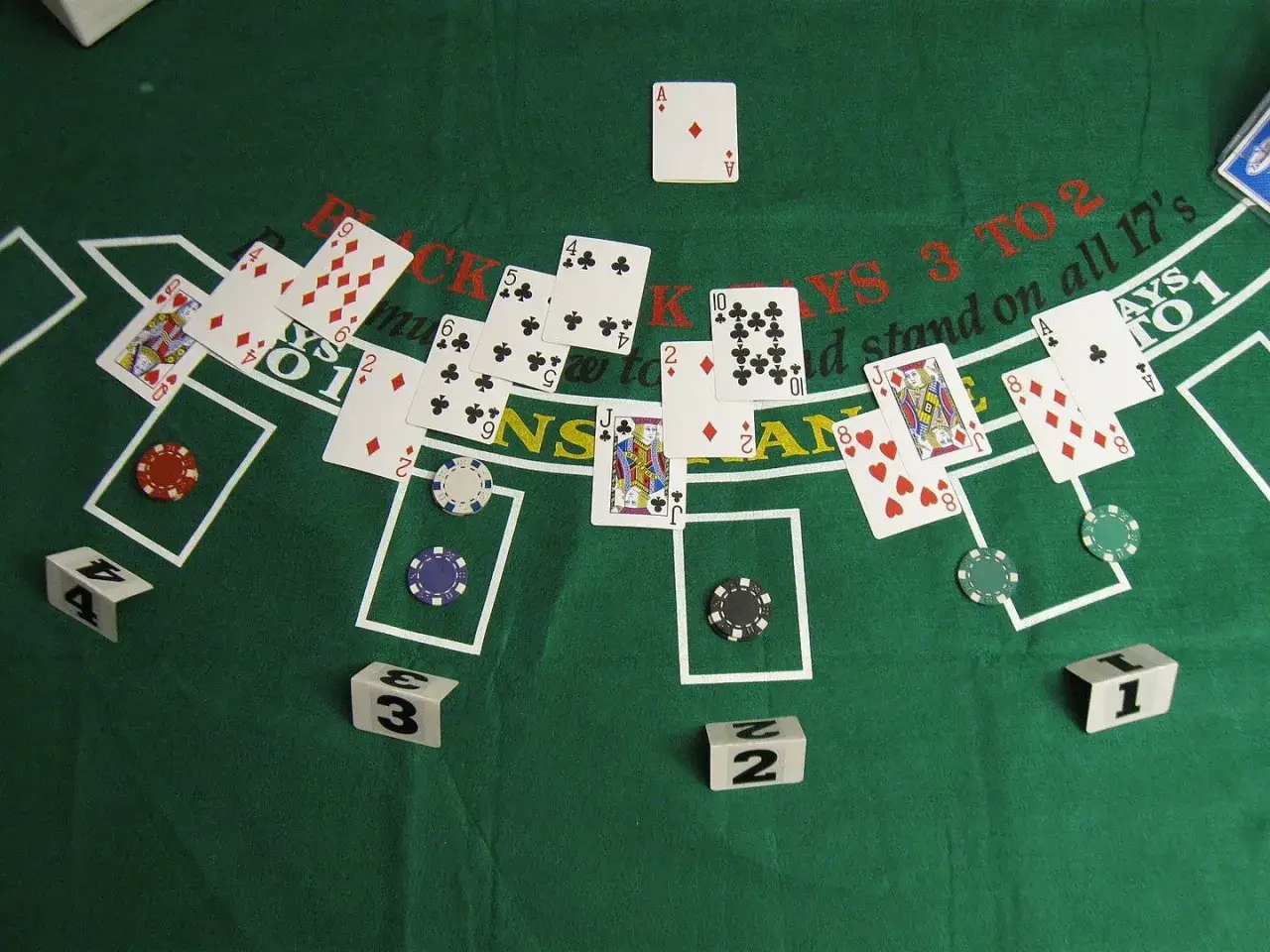 Stół do gry w blackjacka z kartami i żetonami. Widać karty z numerami i figurami, a także kostki z cyframi. To idealne miejsce na emocjonujące gry siódemki.