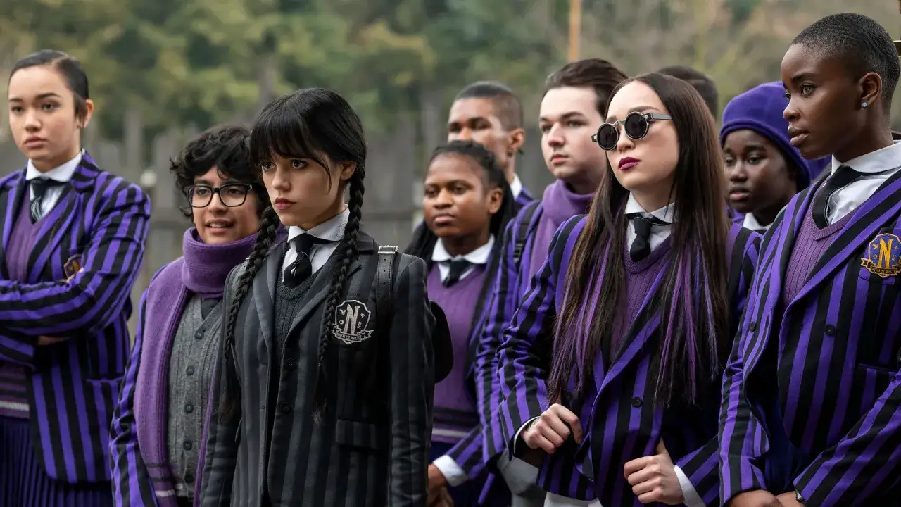 Wednesday postacie w strojach Nevermore. Grupa uczniów w fioletowo-czarnych mundurkach, z Wednesday Addams na pierwszym planie.