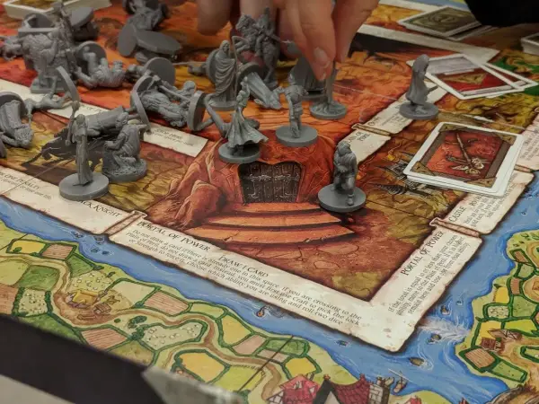 Gra planszowa RPG dla początkujących z figurkami i kartami. Gracze poruszają pionkami po planszy, walcząc i zdobywając przedmioty.