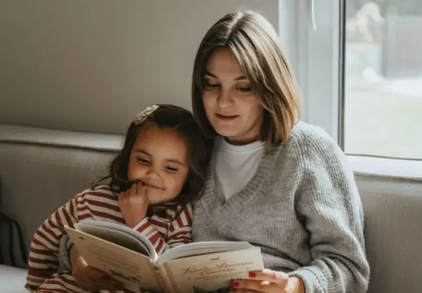 Mama czyta dziecku bajkę, pokazując, jak zachęcić dziecko do czytania. Wspólne chwile z książką budują więź i rozwijają wyobraźnię.