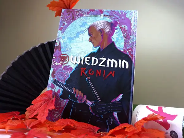 Komiks "Wiedźmin: Ronin" z Geraltem w japońskim stylu, otoczony jesiennymi liśćmi i wachlarzem.