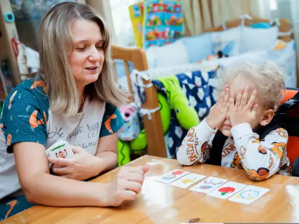 Kreatywne zabawy dla dzieci w wieku szkolnym: mama z synkiem grają w memory, rozwijając pamięć i spostrzegawczość.